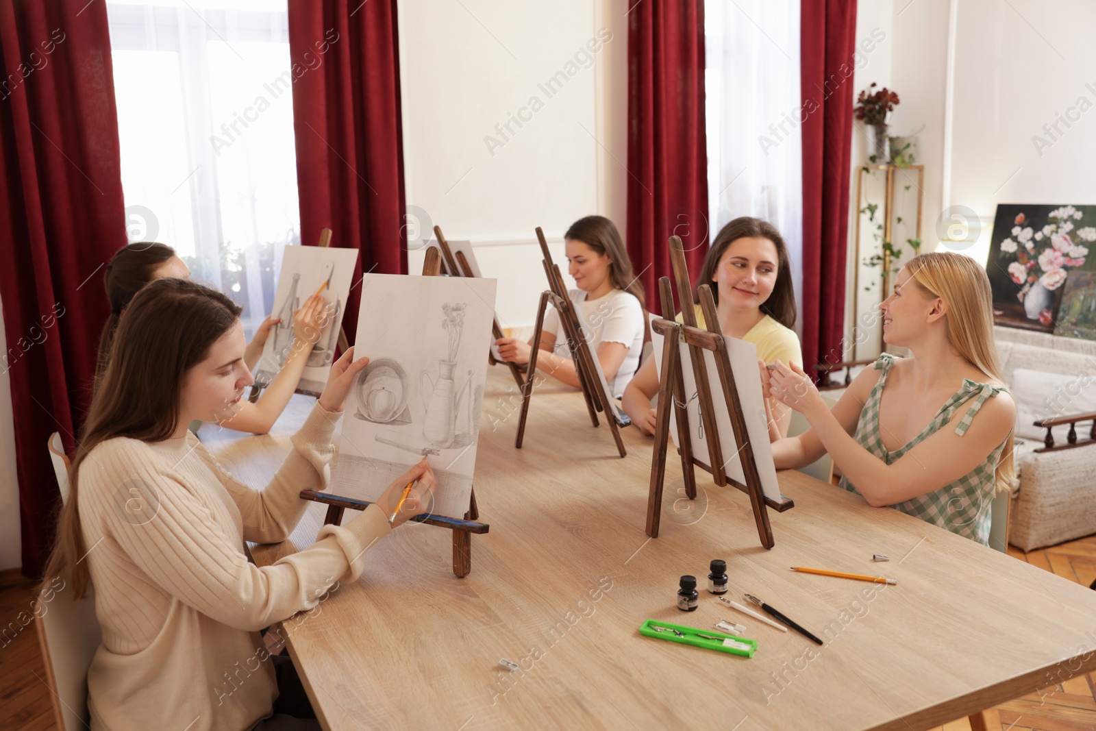 Photo of Group of women learning to draw at wooden table in class