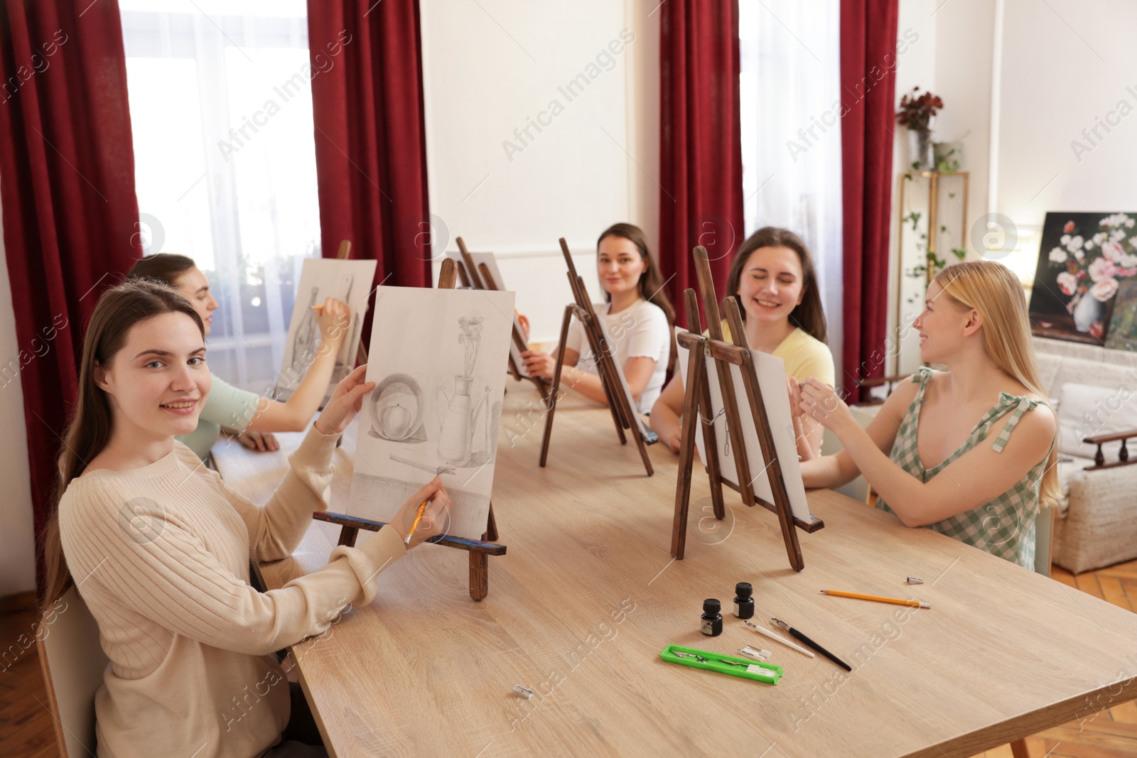 Photo of Group of women learning to draw at wooden table in class