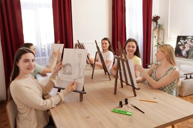 Group of women learning to draw at wooden table in class