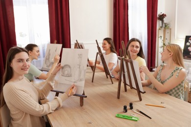 Photo of Group of women learning to draw at wooden table in class