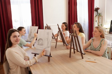 Group of women learning to draw at wooden table in class