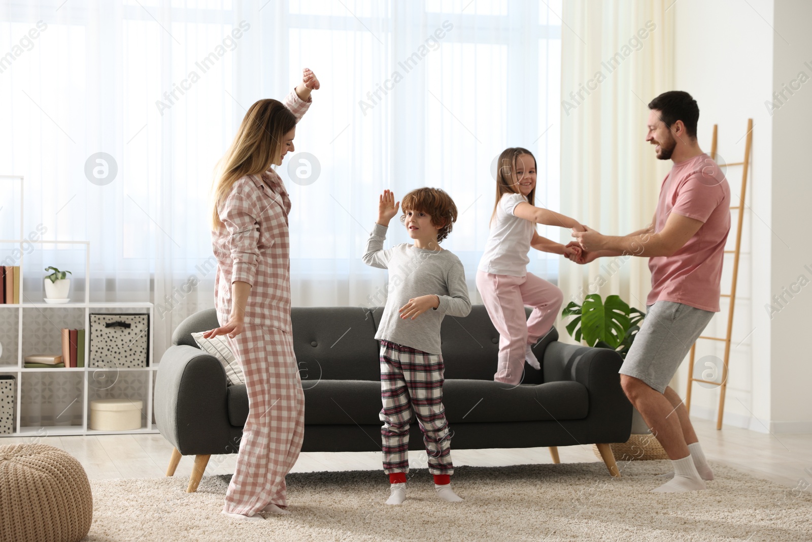 Photo of Happy family wearing stylish pajamas having fun at home