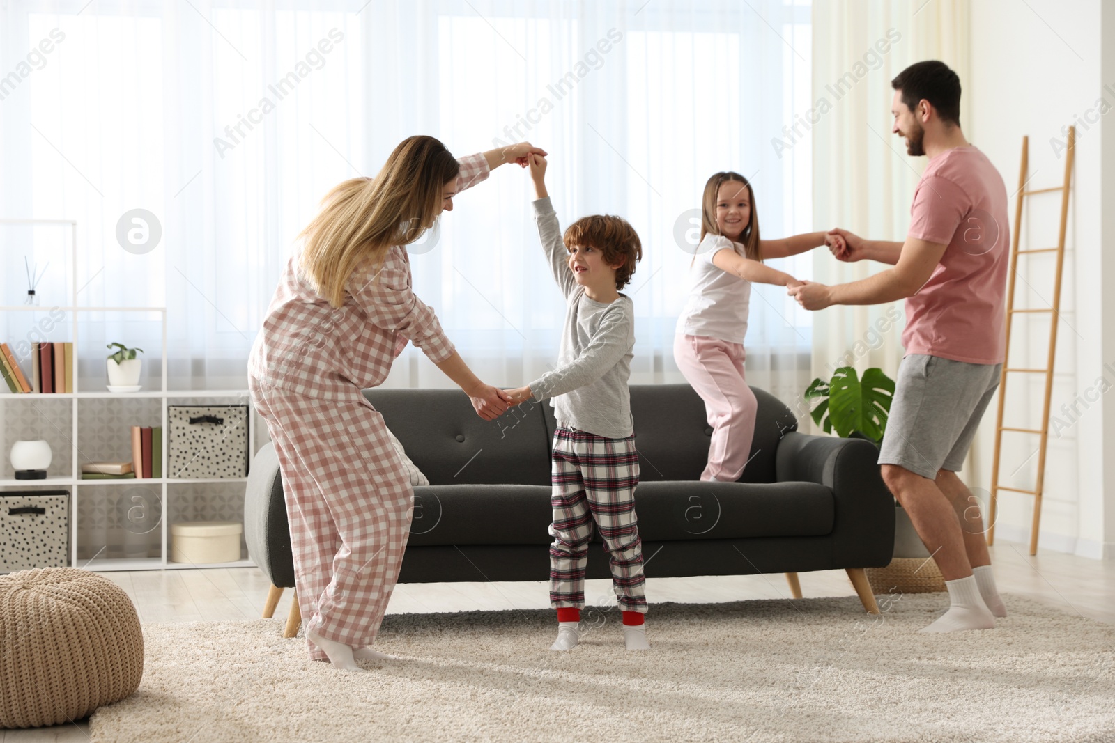 Photo of Happy family wearing stylish pajamas having fun at home