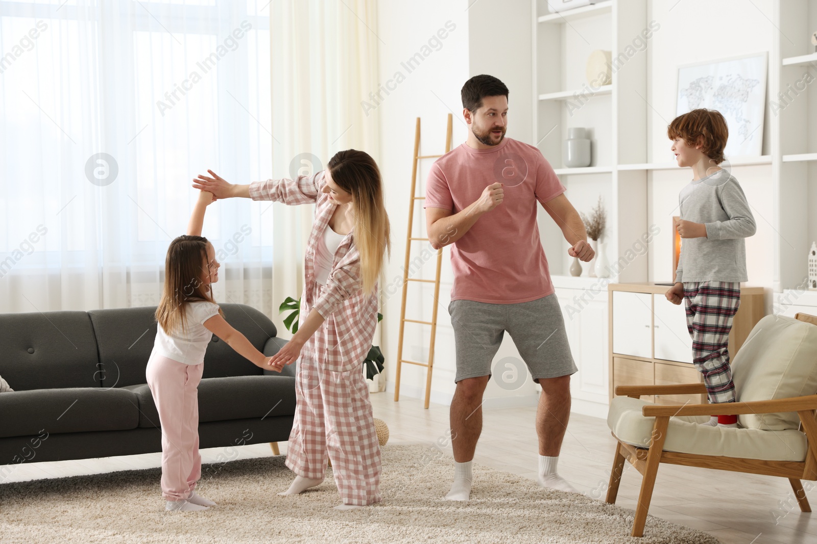 Photo of Happy family wearing stylish pajamas having fun at home