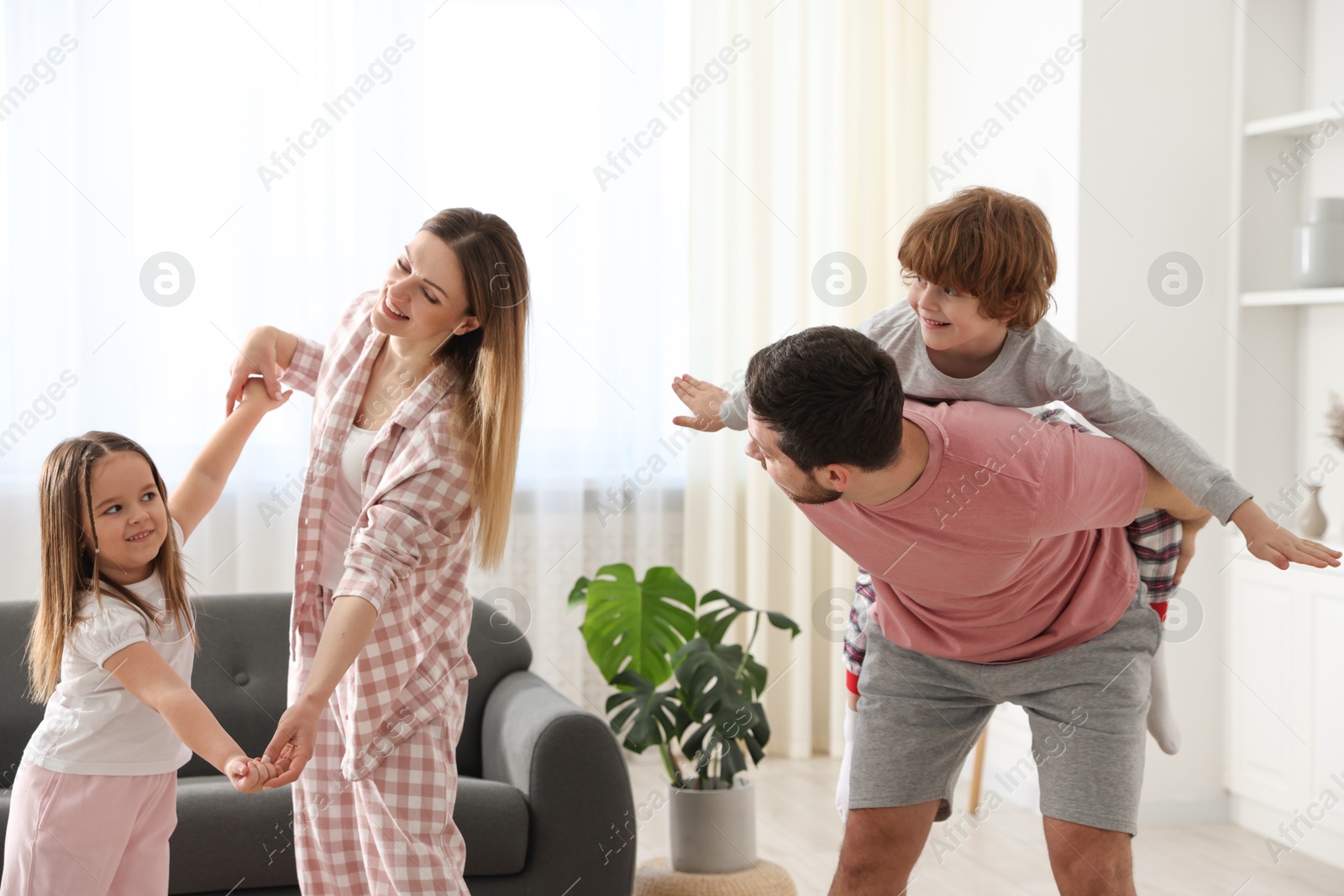 Photo of Happy family wearing stylish pajamas having fun at home