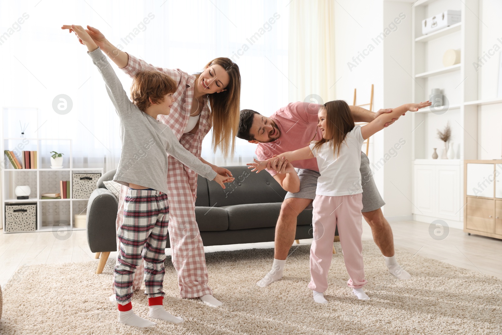 Photo of Happy family wearing stylish pajamas having fun at home