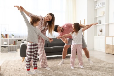 Photo of Happy family wearing stylish pajamas having fun at home