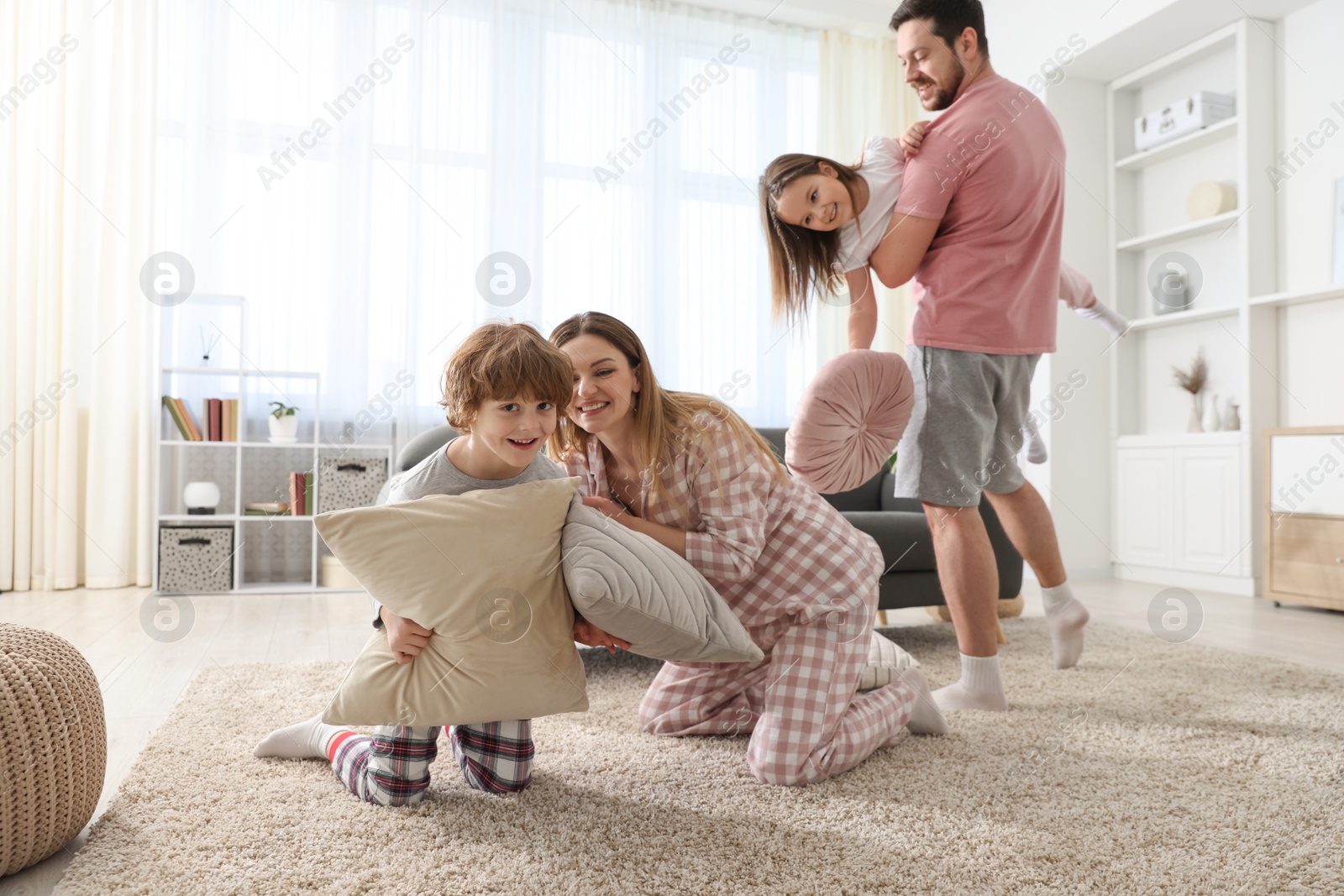 Photo of Happy family wearing pajamas having pillow fight at home