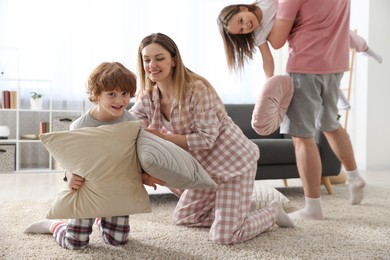 Photo of Happy family wearing pajamas having pillow fight at home