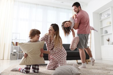 Photo of Happy family wearing pajamas having pillow fight at home