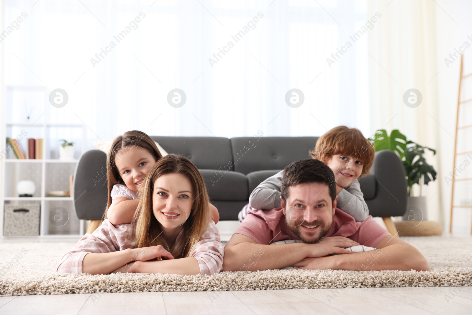 Photo of Family portrait of happy parents and their children wearing stylish pajamas on floor at home