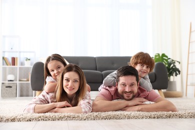 Photo of Family portrait of happy parents and their children wearing stylish pajamas on floor at home