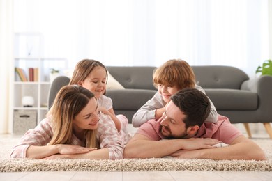 Photo of Family portrait of happy parents and their children wearing stylish pajamas on floor at home