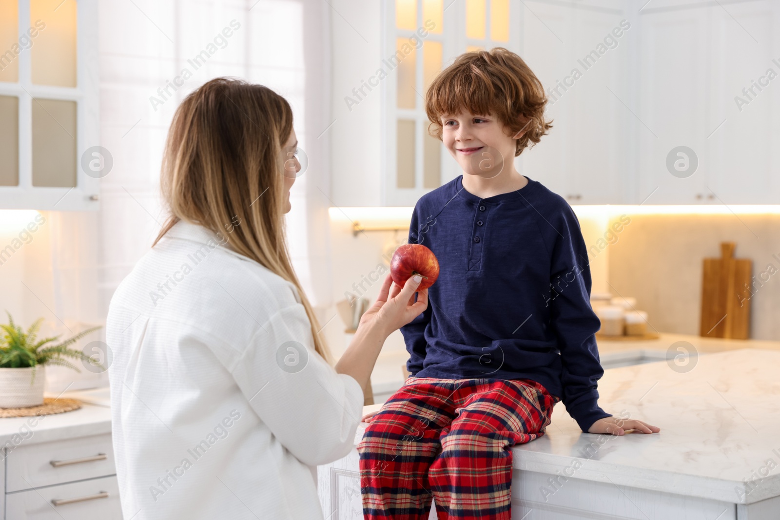 Photo of Woman and her son wearing stylish pajamas spending time together in kitchen