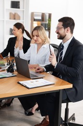 Coworkers working together at wooden table in office