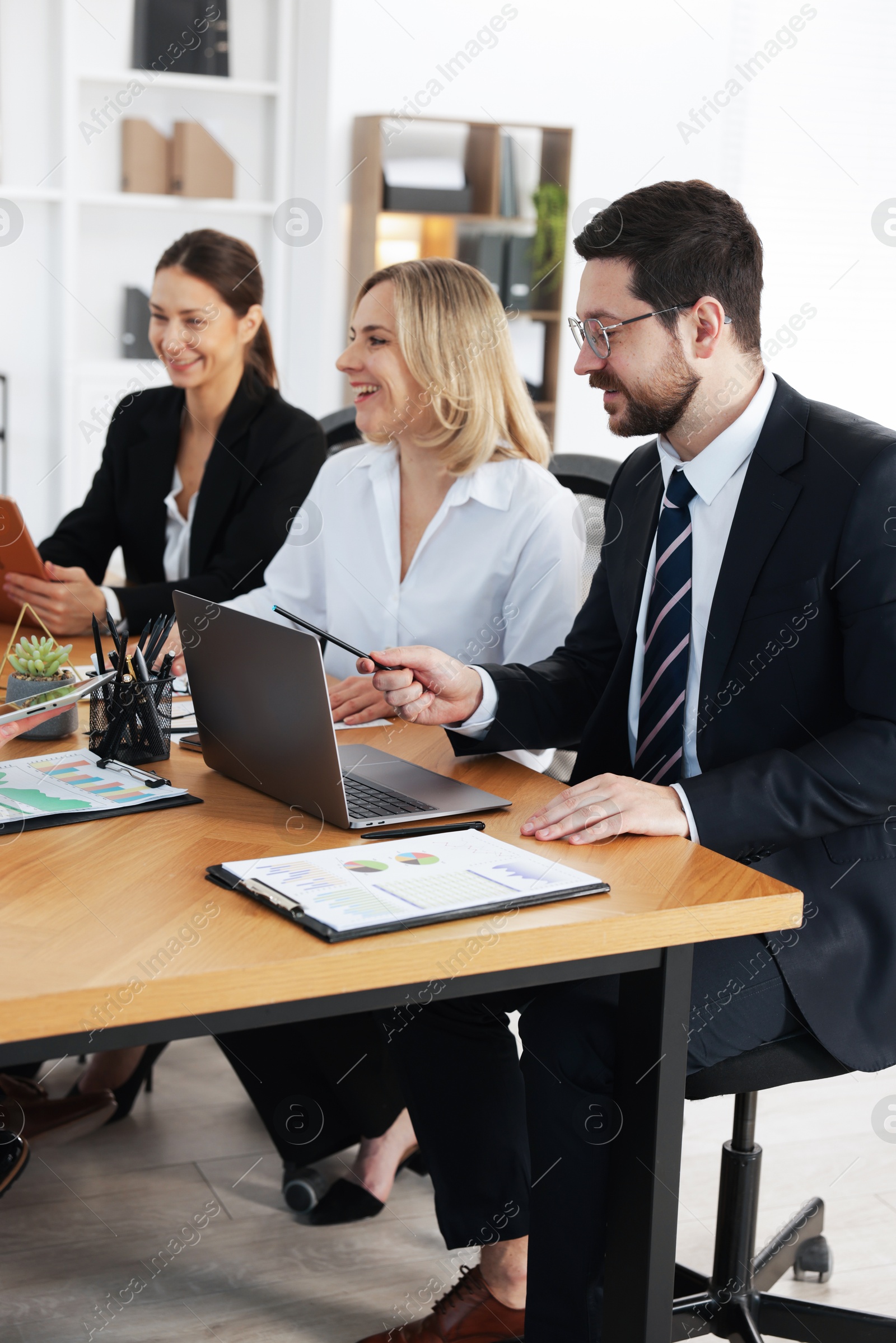 Photo of Coworkers working together at wooden table in office