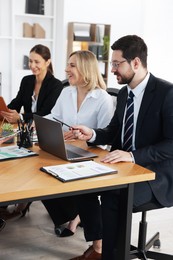 Coworkers working together at wooden table in office