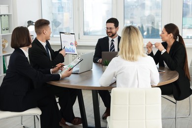 Coworkers working together at wooden table in office