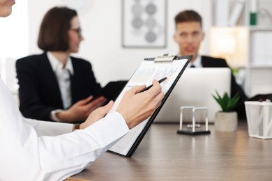 Coworkers working together at wooden table in office, selective focus