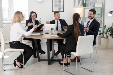 Photo of Coworkers working together at wooden table in office