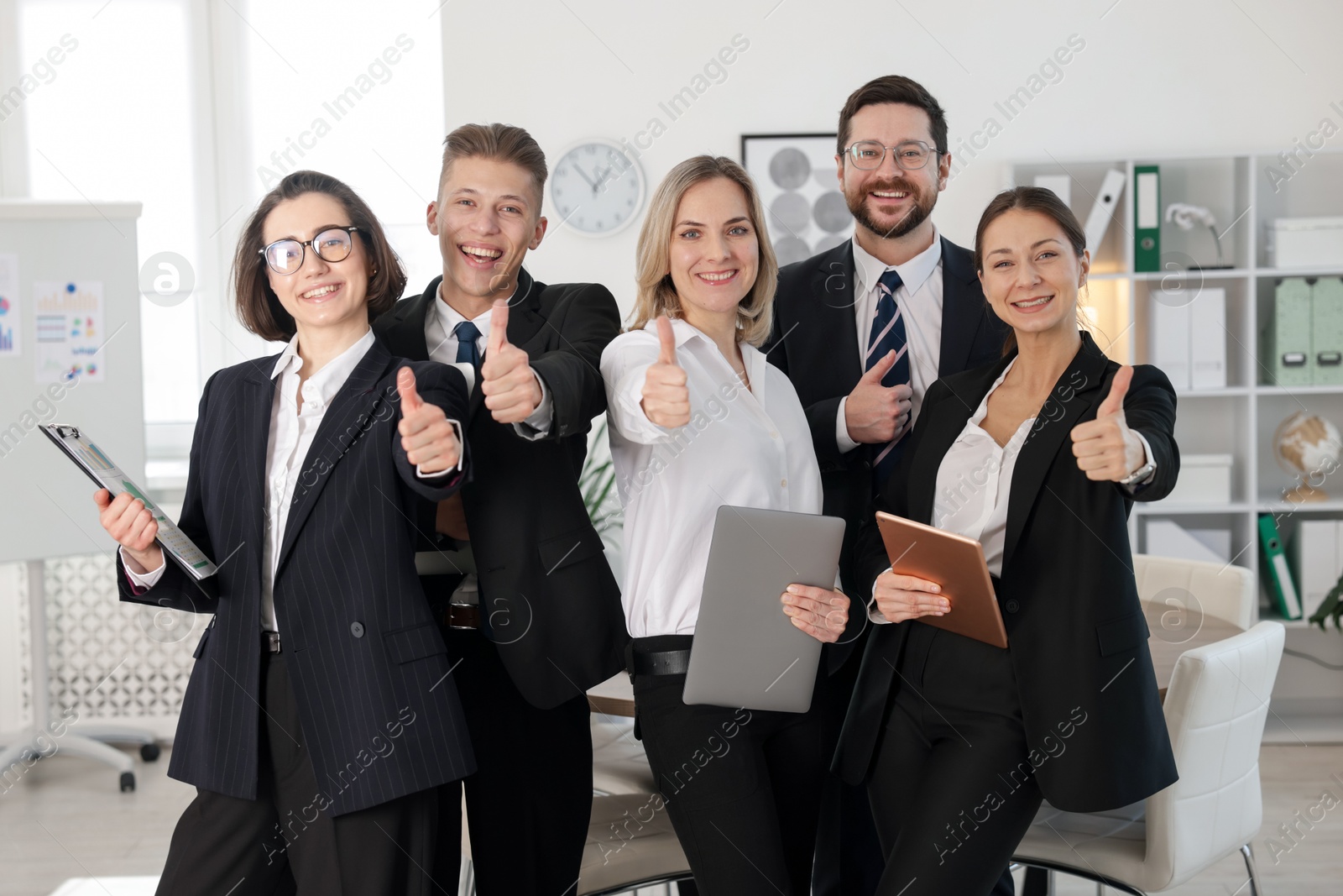 Photo of Happy coworkers showing thumbs up in office