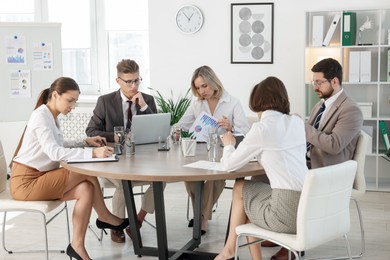 Coworkers working together at wooden table in office