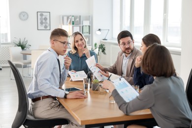 Coworkers working together at wooden table in office