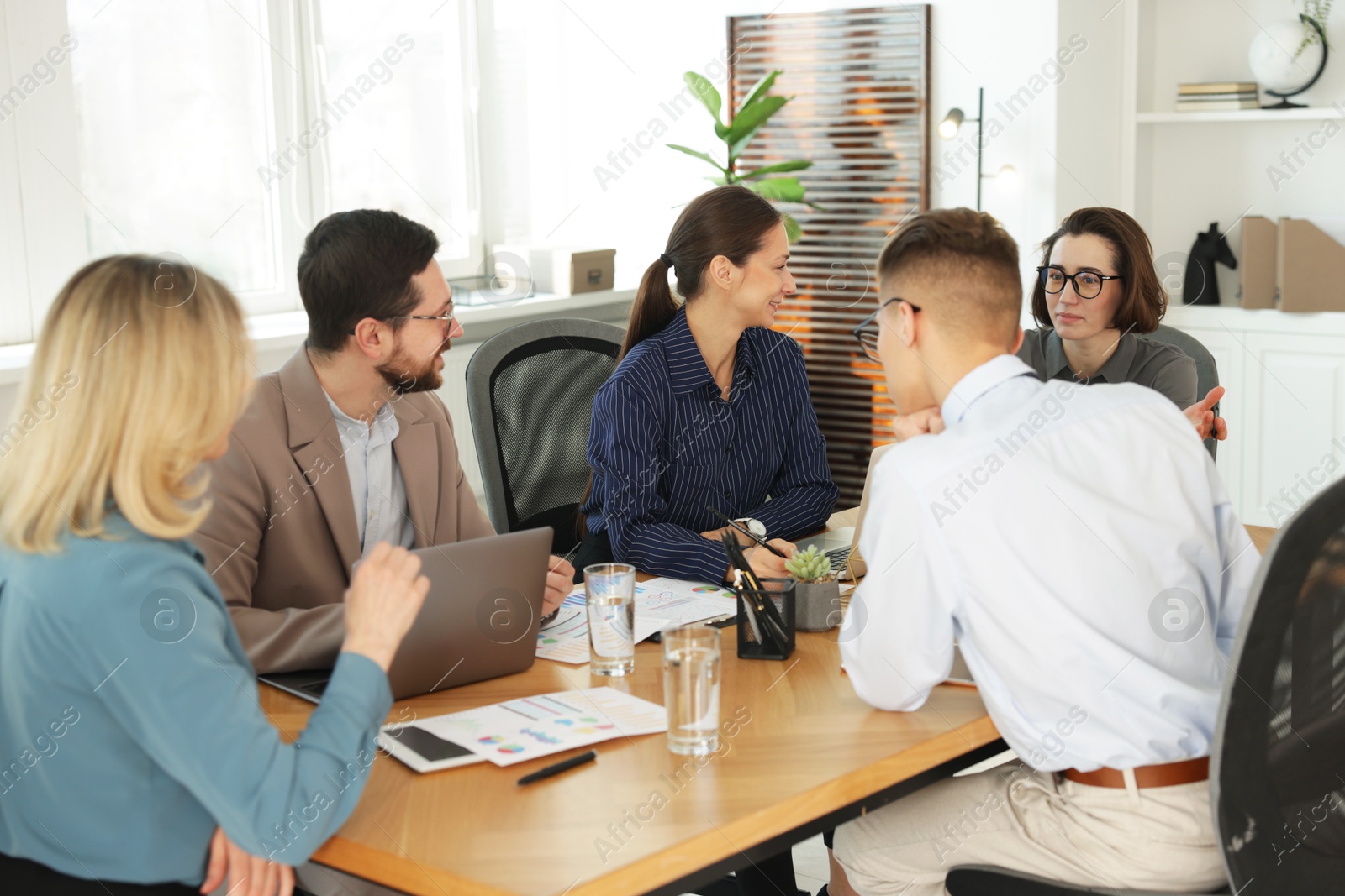 Photo of Coworkers working together at wooden table in office