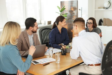 Coworkers working together at wooden table in office