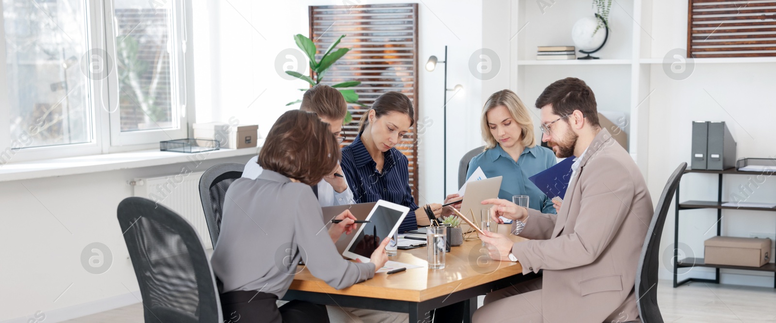 Photo of Coworkers working together at wooden table in office