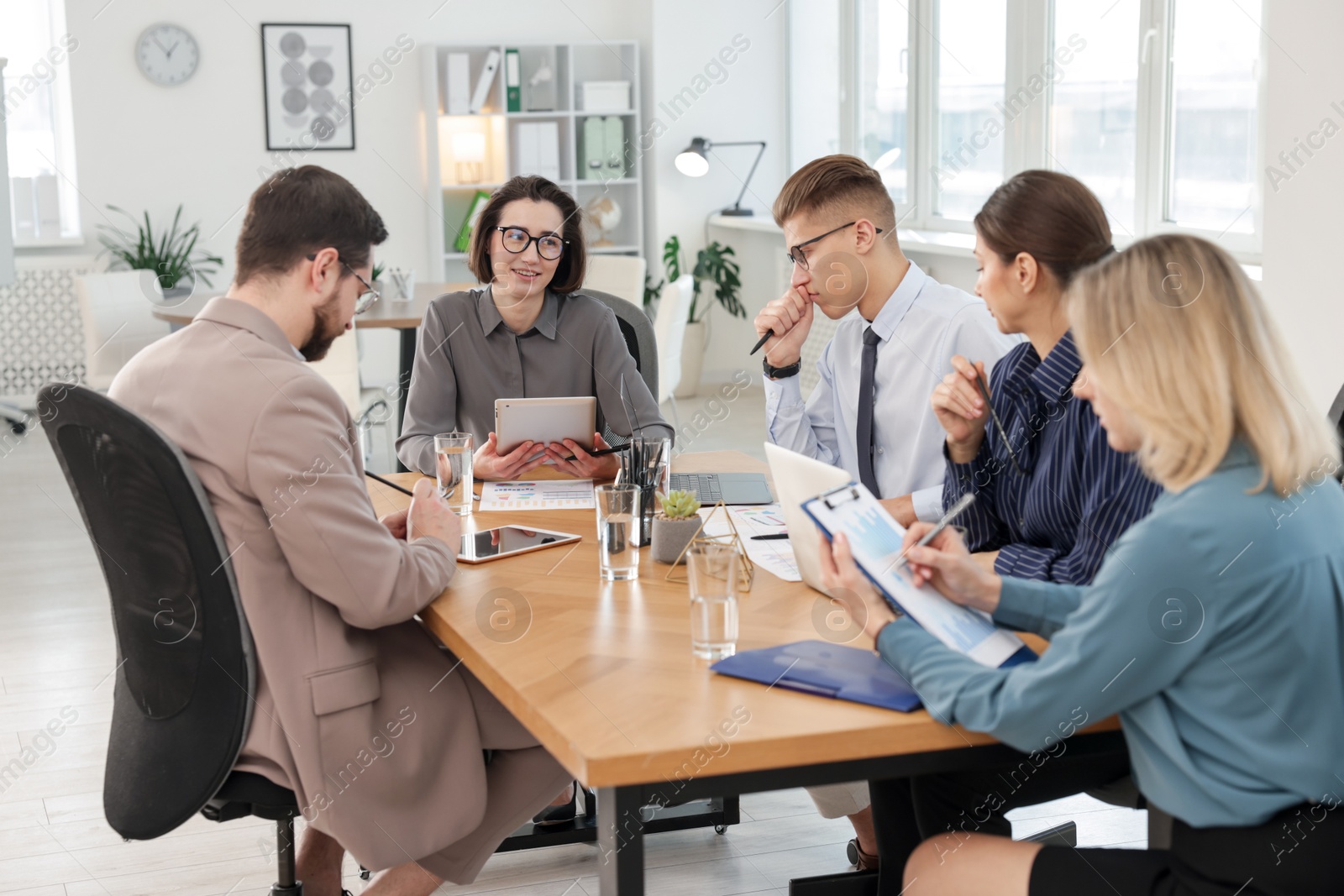 Photo of Coworkers working together at wooden table in office