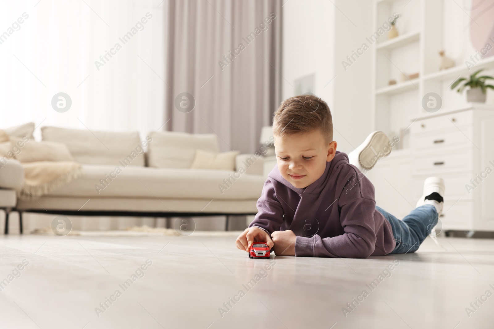 Photo of Little boy playing with toy car at home. Space for text