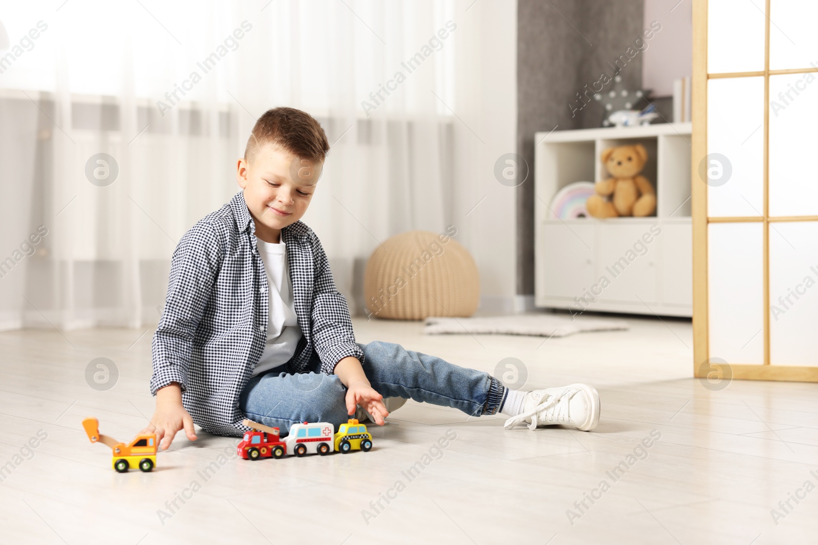 Photo of Little boy playing with toy cars at home. Space for text