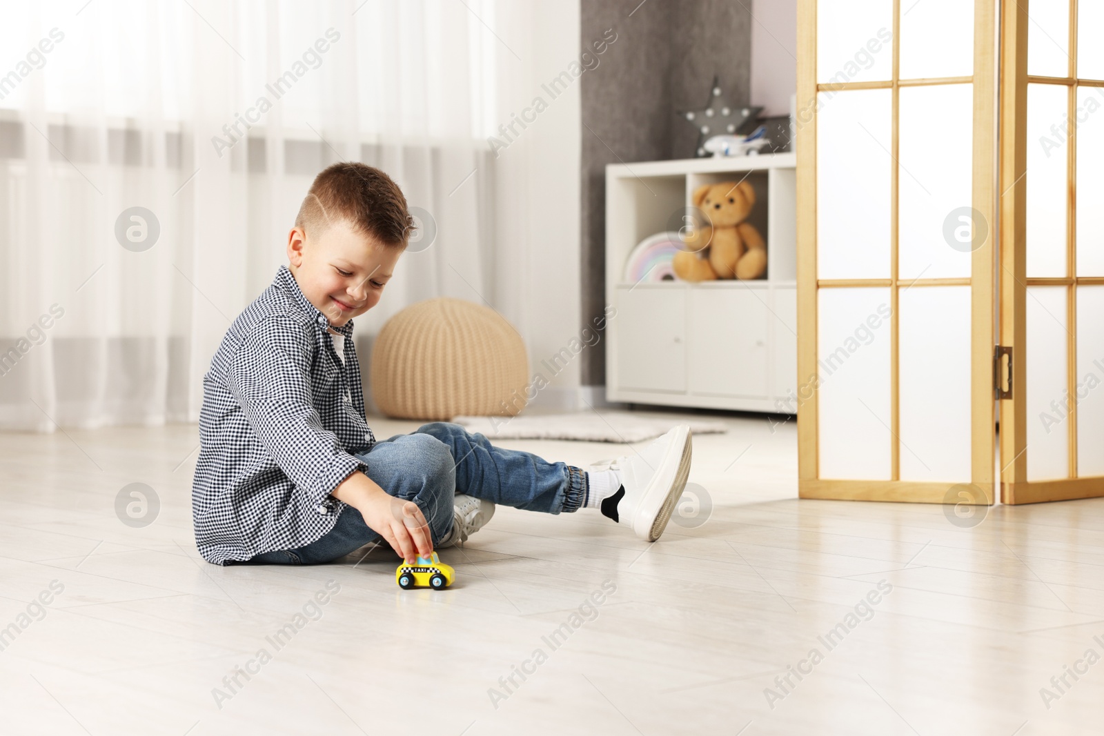 Photo of Little boy playing with toy car at home. Space for text