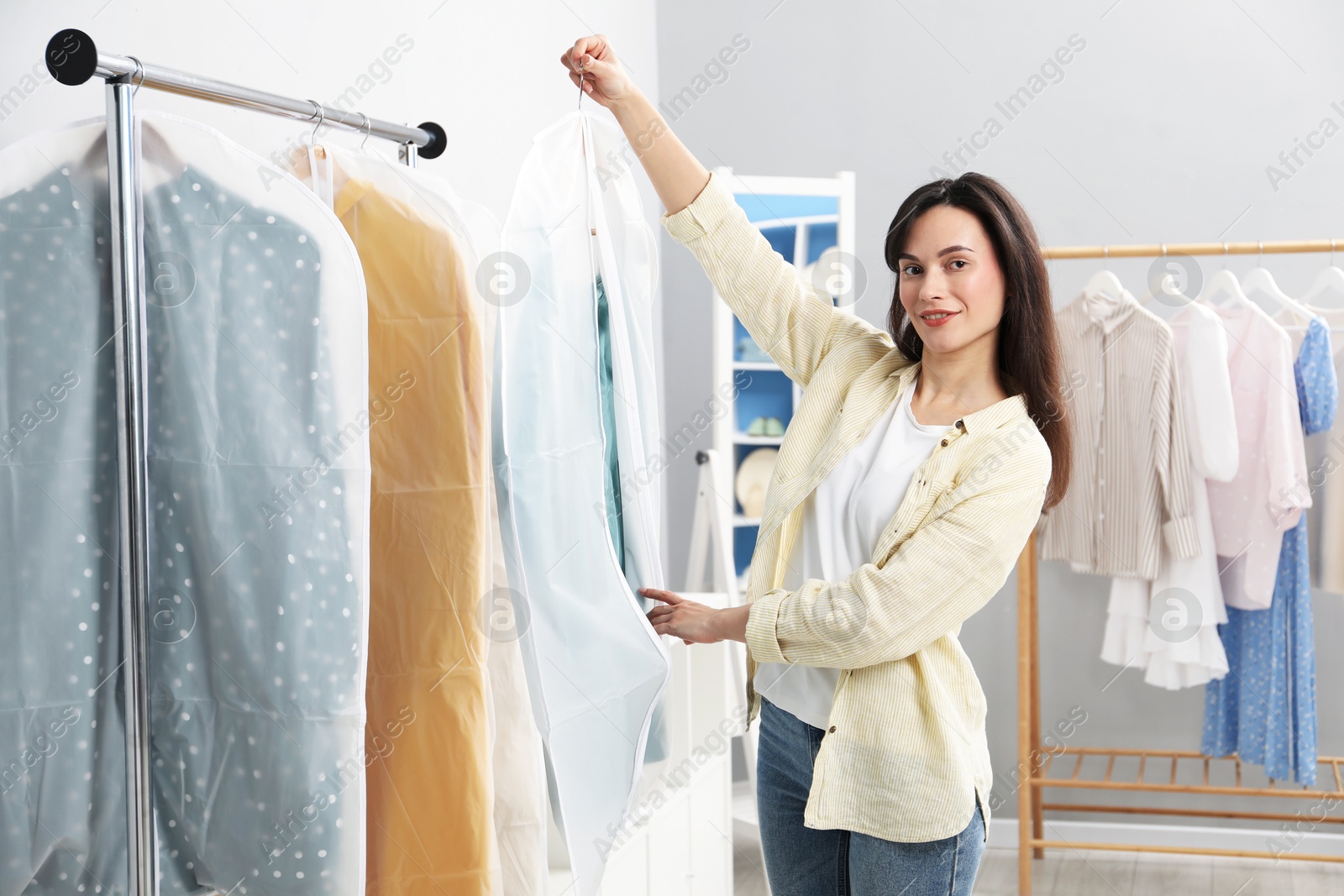 Photo of Woman holding garment cover with clothes indoors