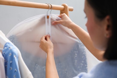 Photo of Woman zipping garment cover with clothes indoors, closeup