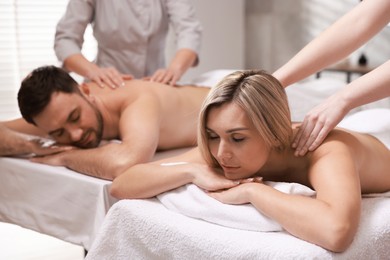 Photo of Couple receiving relaxing massage in spa salon, selective focus