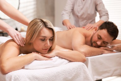 Photo of Couple receiving relaxing massage in spa salon, selective focus