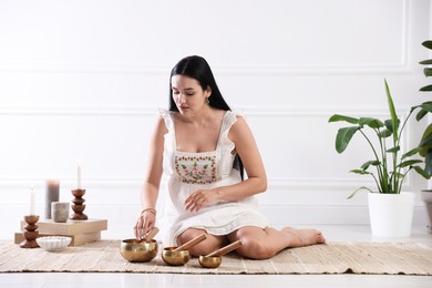 Photo of Woman with singing bowls on floor indoors