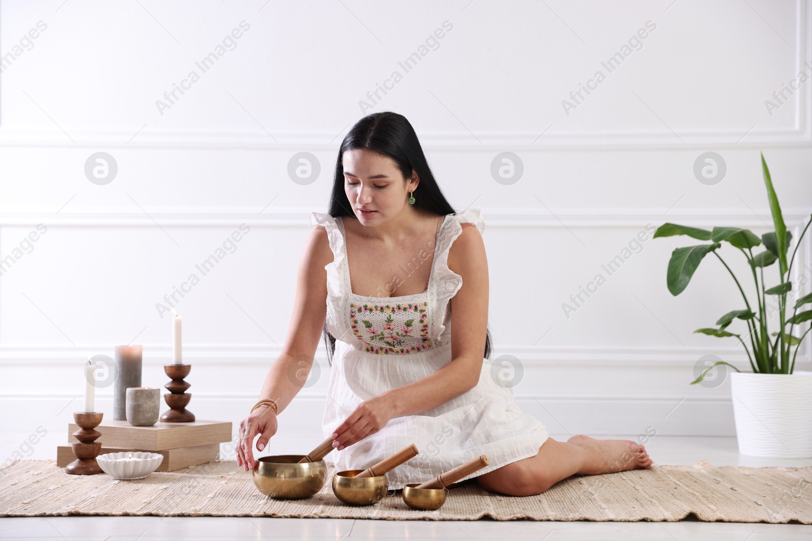 Photo of Woman with singing bowls on floor indoors