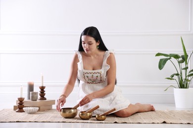 Photo of Woman with singing bowls on floor indoors