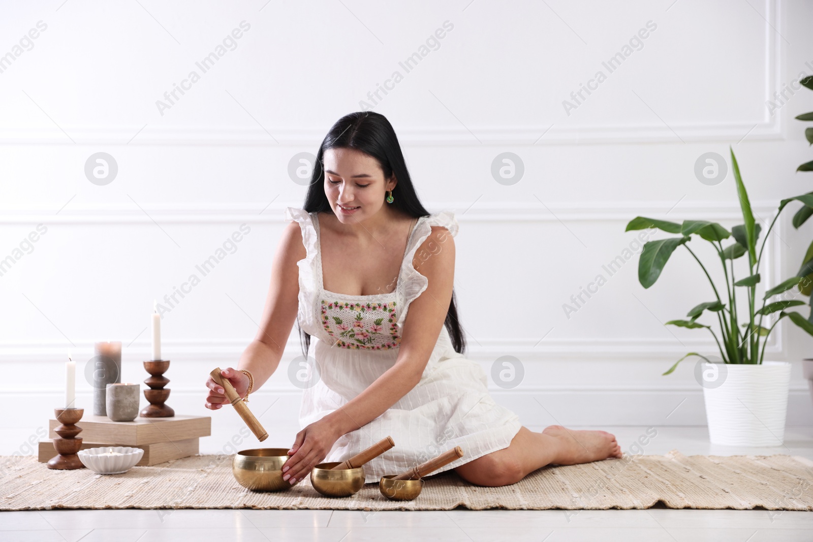 Photo of Woman with singing bowls on floor indoors