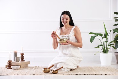 Photo of Woman with singing bowls on floor indoors. Space for text