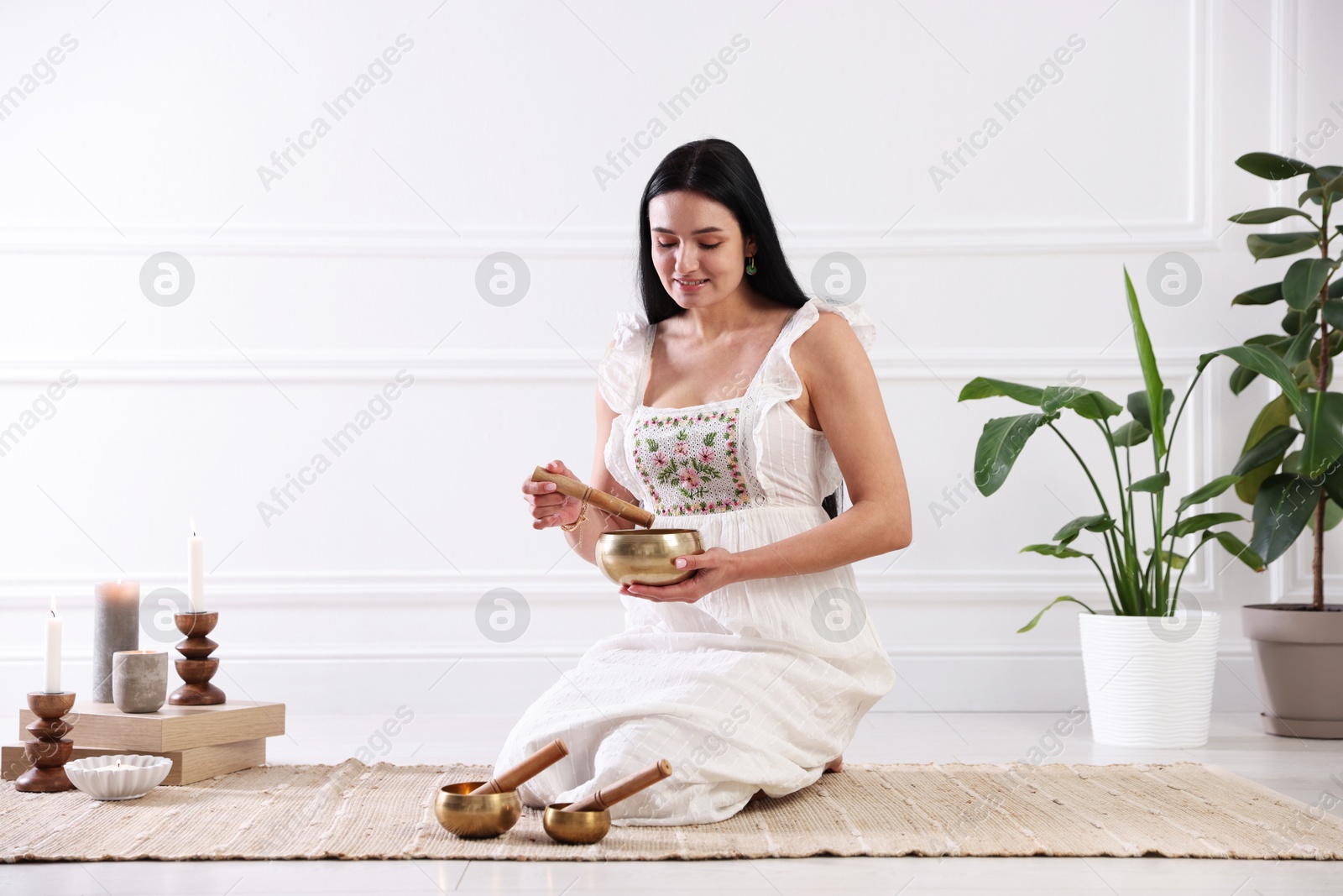 Photo of Woman with singing bowls on floor indoors