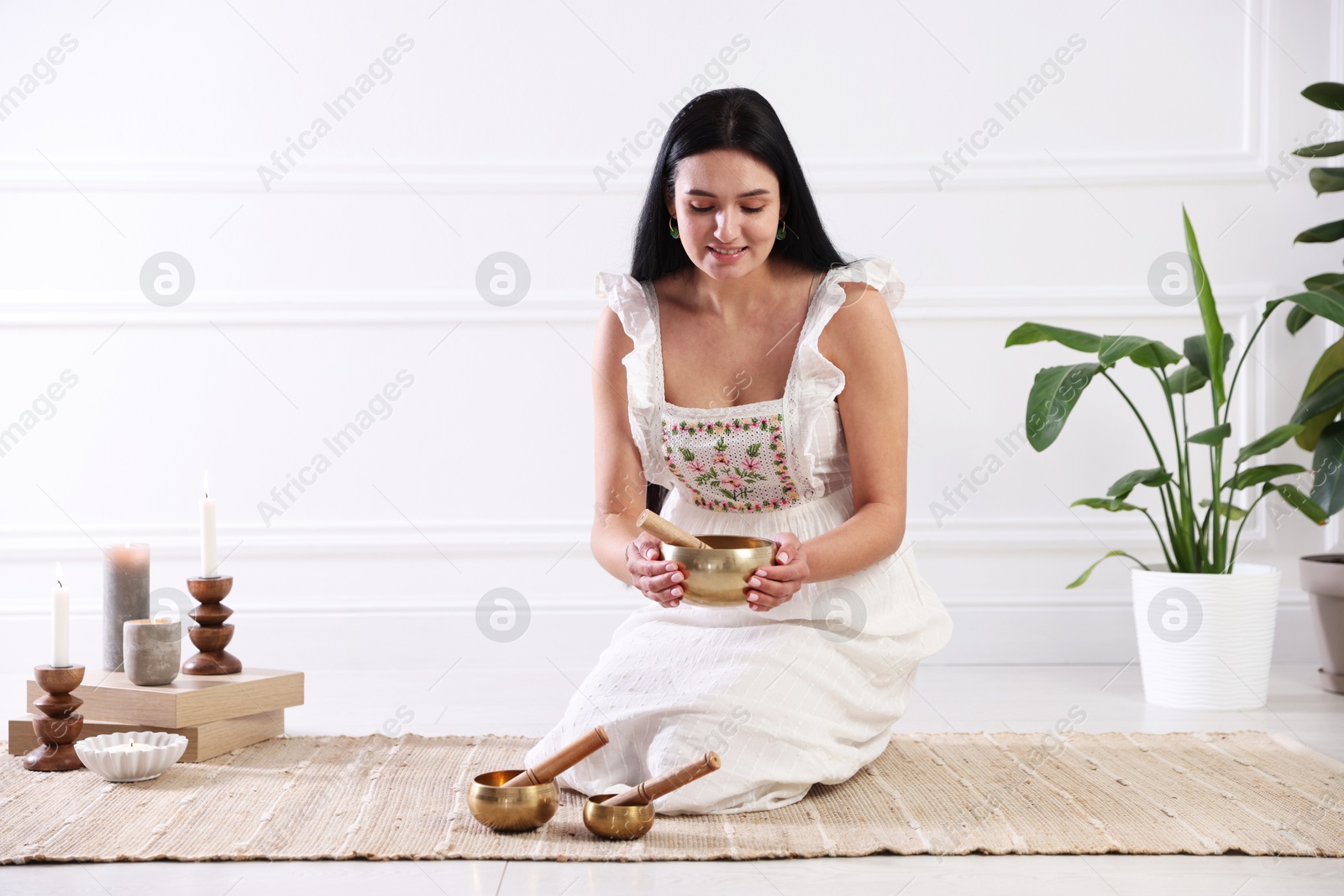 Photo of Woman with singing bowls on floor indoors