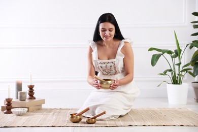 Photo of Woman with singing bowls on floor indoors