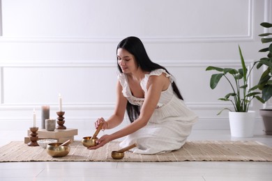 Photo of Woman with singing bowls on floor indoors