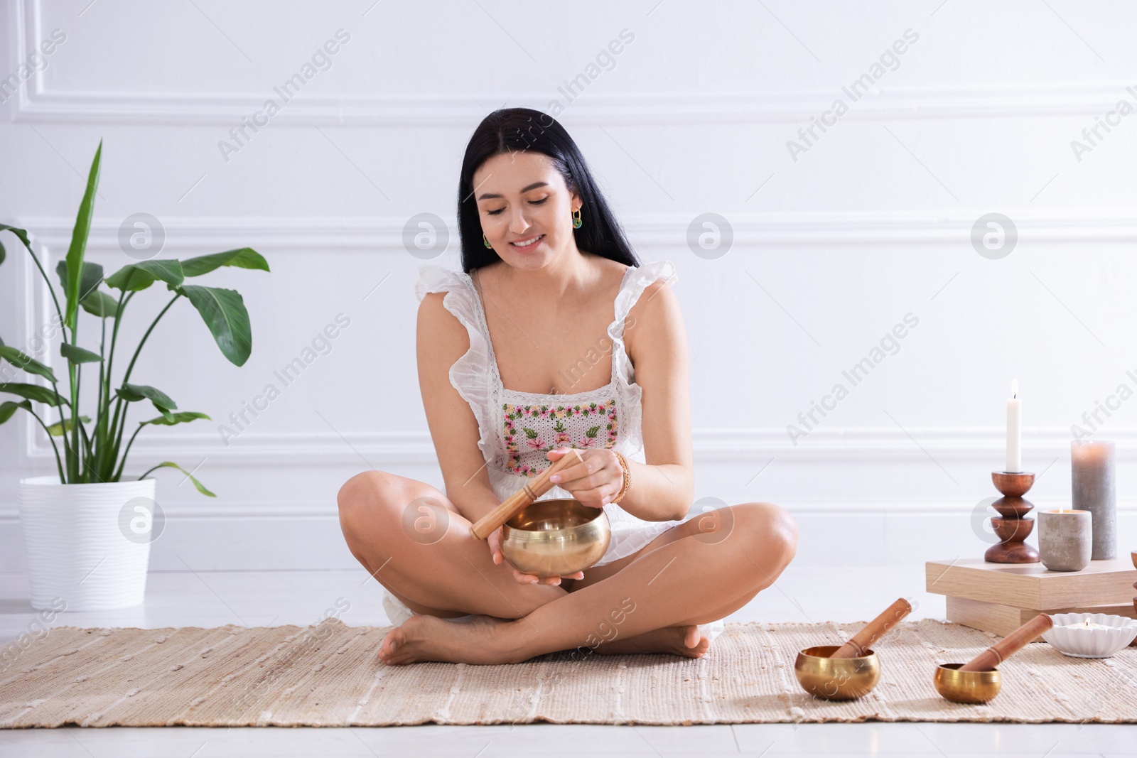 Photo of Woman with singing bowls on floor indoors