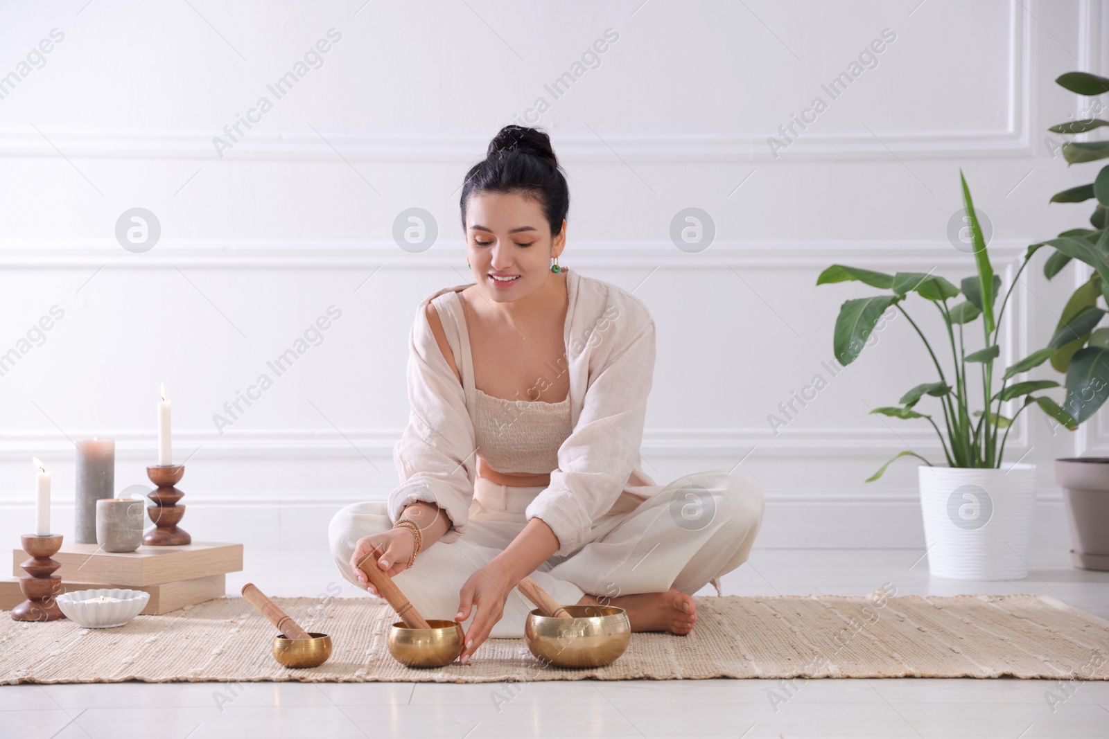 Photo of Woman with singing bowls on floor indoors