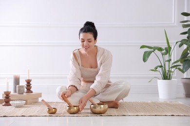 Photo of Woman with singing bowls on floor indoors